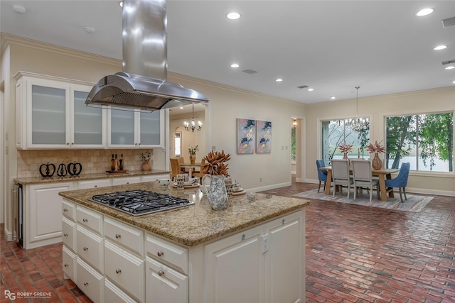 1078 Waters Edge Cir, Shreveport, LA 71106 - kitchen featuring island exhaust hood, stainless steel gas stovetop, brick flooring, crown molding, and a chandelier