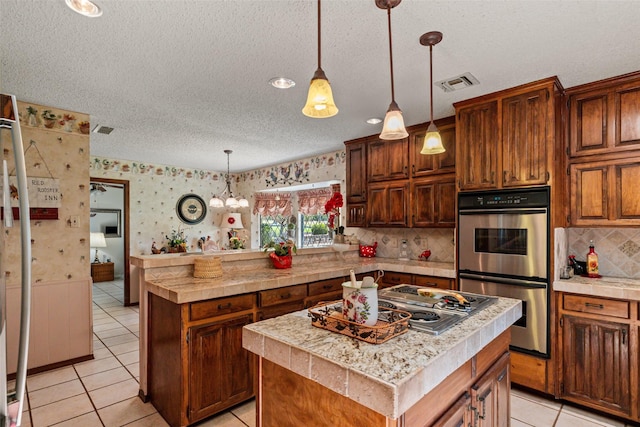 3503 Red Bud Dr, Weatherford, TX 76087 - kitchen with stainless steel appliances, wallpapered walls, light tile patterned flooring, a center island, and a peninsula