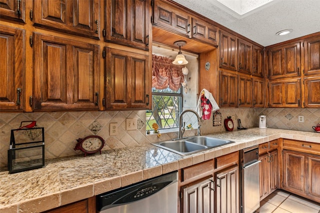 3503 Red Bud Dr, Weatherford, TX 76087 - kitchen with stainless steel dishwasher, light countertops, tasteful backsplash, light tile patterned floors, and brown cabinetry