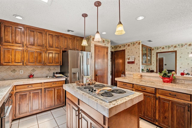 3503 Red Bud Dr, Weatherford, TX 76087 - kitchen featuring appliances with stainless steel finishes, wallpapered walls, a textured ceiling, a center island, and brown cabinetry