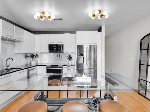 1122 Jackson St Unit 1103, Dallas, TX 75202 - kitchen with stainless steel appliances, light wood-style flooring, modern cabinets, and white cabinets