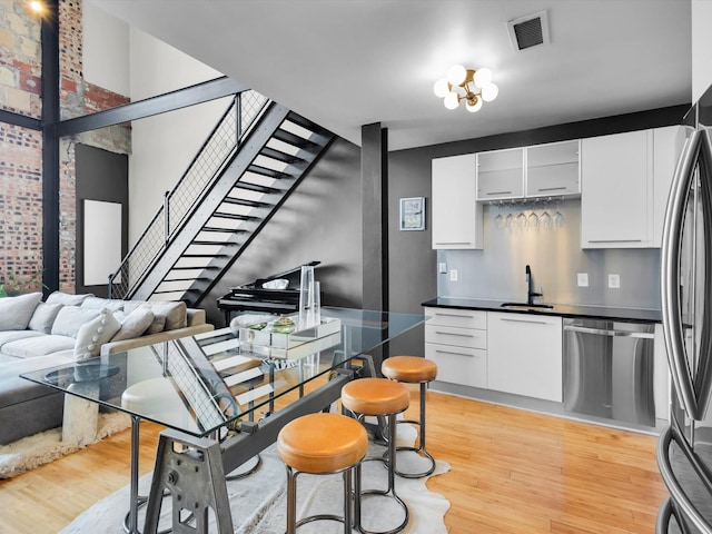1122 Jackson St Unit 1103, Dallas, TX 75202 - kitchen featuring stainless steel appliances, light wood-style floors, white cabinets, and dark countertops