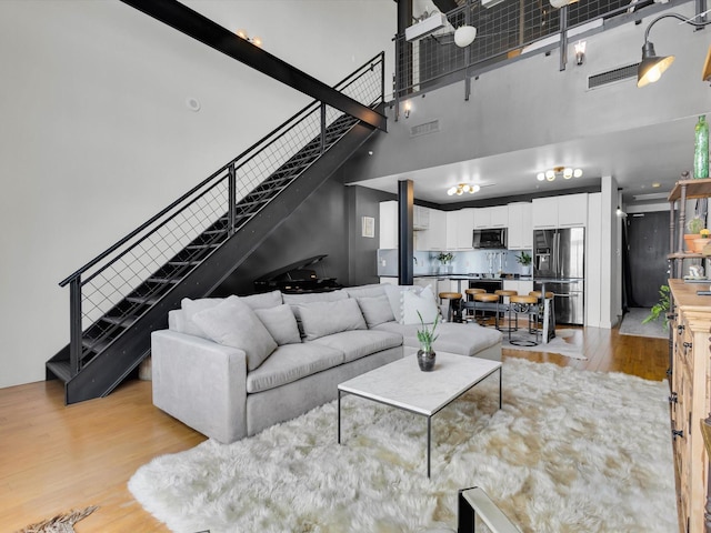 1122 Jackson St Unit 1103, Dallas, TX 75202 - living room featuring a high ceiling, stairs, and light wood-style floors