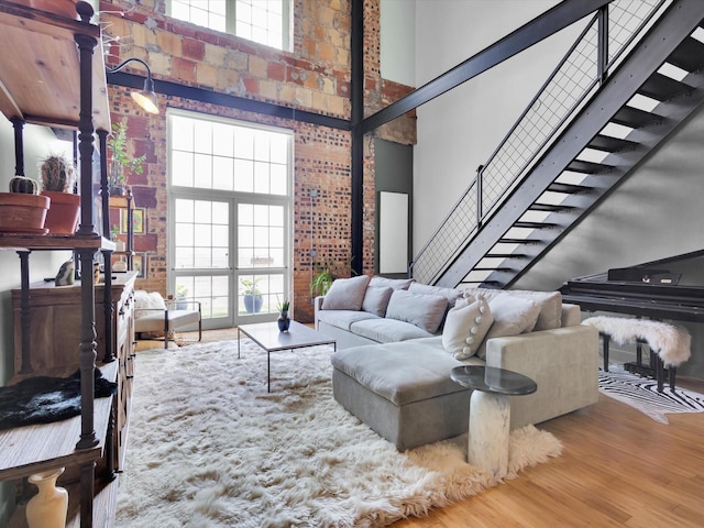 1122 Jackson St Unit 1103, Dallas, TX 75202 - living area with a towering ceiling, stairs, wood finished floors, and brick wall