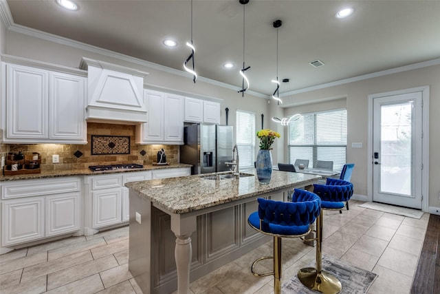 751 Devonshire Ct, Prosper, TX 75078 - kitchen with stainless steel appliances, custom range hood, an island with sink, backsplash, and light stone counters