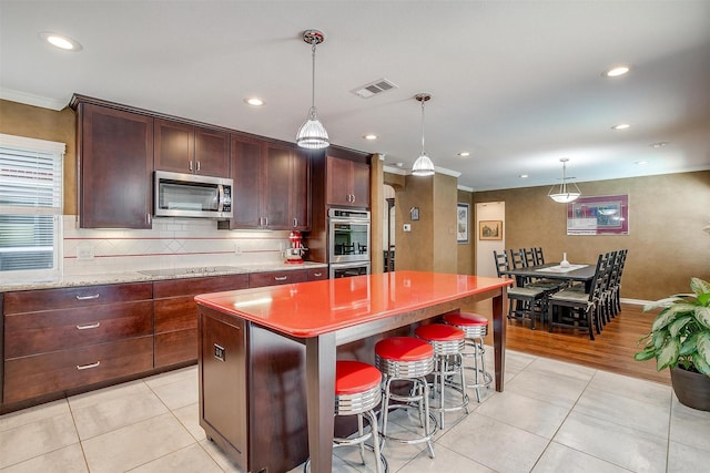 609 Huntington Ct, Grapevine, TX 76051 - kitchen featuring appliances with stainless steel finishes, a kitchen island, recessed lighting, light tile patterned floors, and crown molding