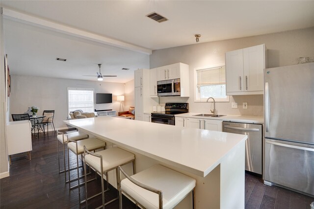 5712 Hudson St, Dallas, TX 75206 - kitchen featuring stainless steel appliances, a breakfast bar area, healthy amount of natural light, and dark wood finished floors