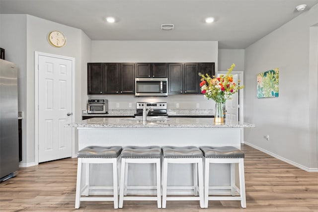 7209 Guadalupe Rd, China Spring, TX 76633 - kitchen featuring stainless steel appliances, light wood-style flooring, a breakfast bar, a kitchen island with sink, and recessed lighting
