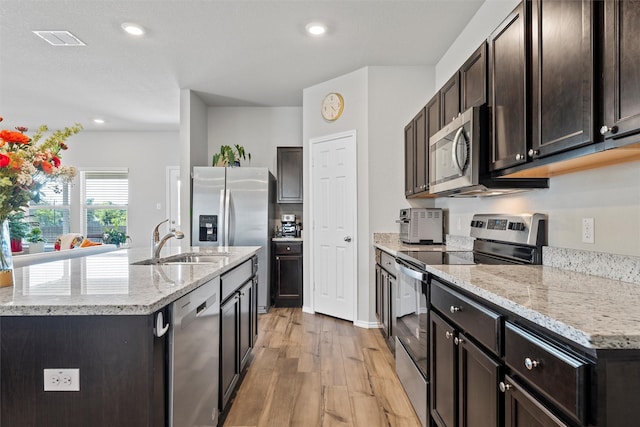 7209 Guadalupe Rd, China Spring, TX 76633 - kitchen with appliances with stainless steel finishes, light wood finished floors, an island with sink, dark brown cabinetry, and recessed lighting