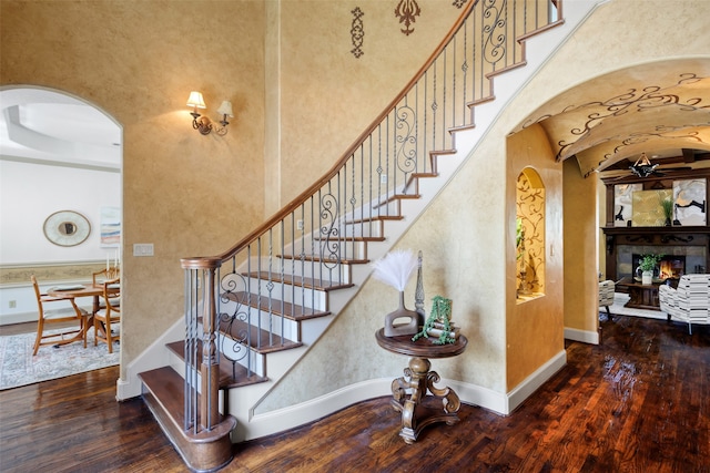 5101 Oak Timbers Ct, Colleyville, TX 76034 - staircase with arched walkways, wood finished floors, ceiling fan, and a warm lit fireplace