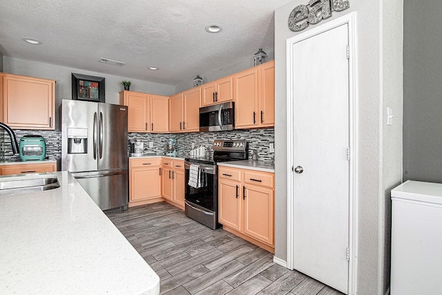 7400 Howling Coyote Ln, Fort Worth, TX 76131 - kitchen featuring appliances with stainless steel finishes, light brown cabinetry, light countertops, decorative backsplash, and light wood finished floors