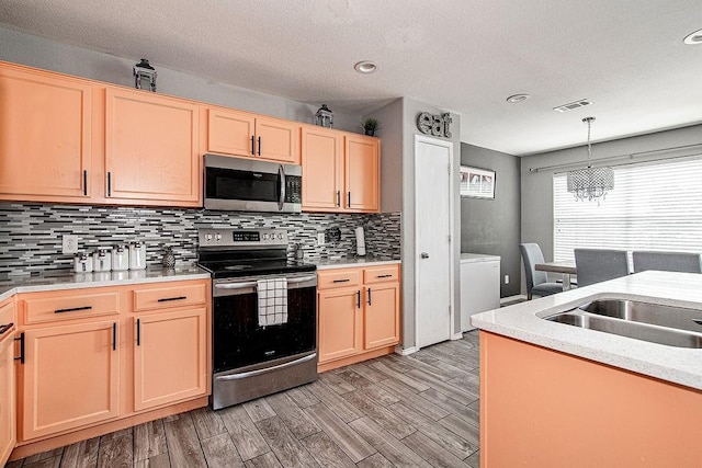 7400 Howling Coyote Ln, Fort Worth, TX 76131 - kitchen featuring appliances with stainless steel finishes, backsplash, light brown cabinetry, light countertops, and a chandelier