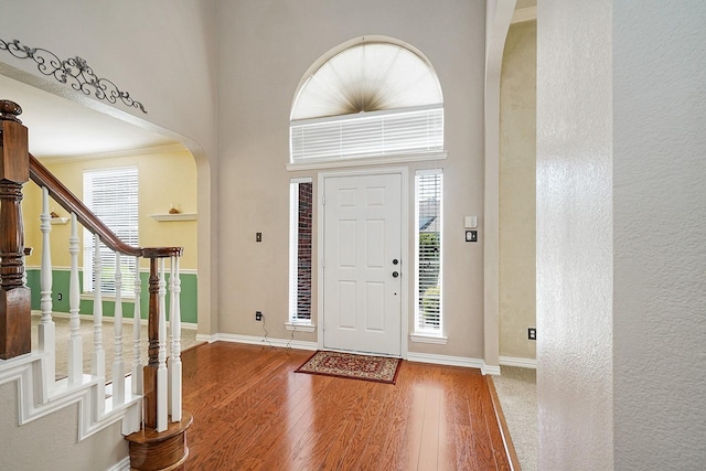 9513 Tiger Dr, Plano, TX 75025 - foyer entrance featuring arched walkways, wood finished floors, stairway, a high ceiling, and a textured wall