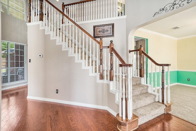 9513 Tiger Dr, Plano, TX 75025 - staircase featuring wood finished floors, arched walkways, ornamental molding, and a high ceiling