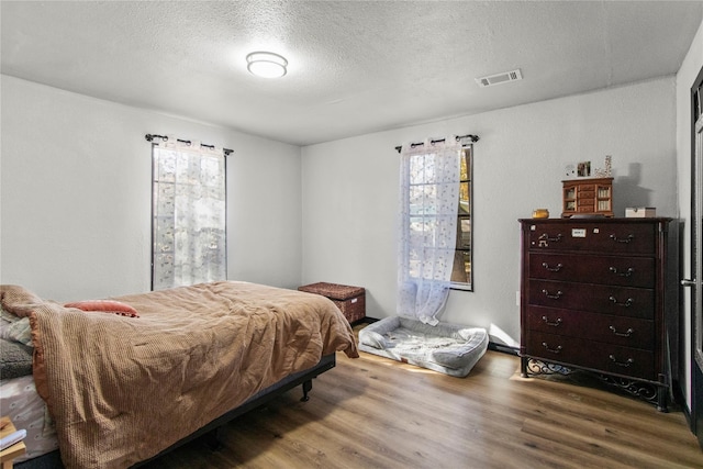 1054 Frontage Rd, Minden, LA 71055 - bedroom with multiple windows, wood finished floors, and a textured ceiling