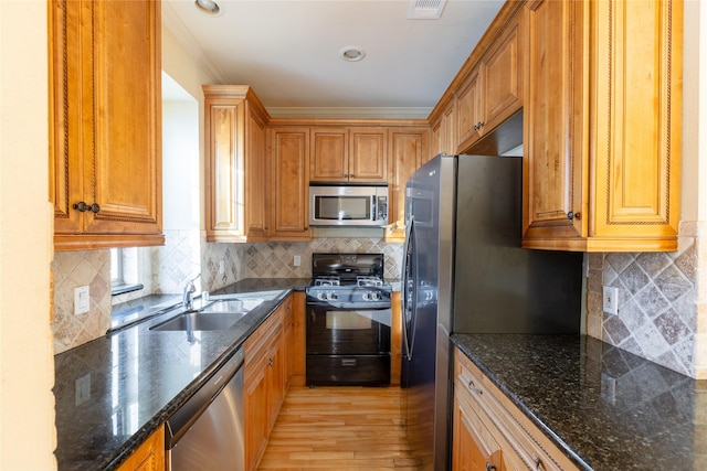 2203 N Carroll Ave Unit 1, Dallas, TX 75204 - kitchen with appliances with stainless steel finishes, light wood finished floors, brown cabinetry, tasteful backsplash, and crown molding