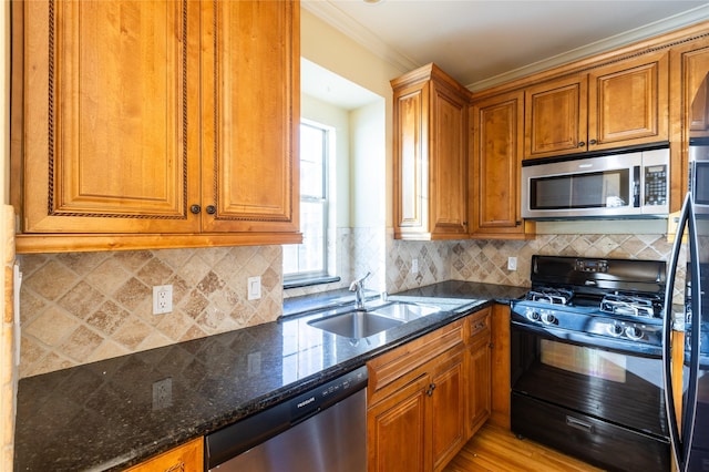 2203 N Carroll Ave Unit 1, Dallas, TX 75204 - kitchen with appliances with stainless steel finishes, dark stone countertops, brown cabinetry, light wood-type flooring, and crown molding