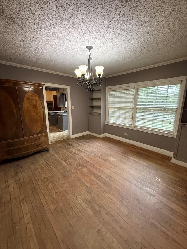 709 Highland Dr, Palestine, TX 75801 - unfurnished dining area featuring ornamental molding, a textured ceiling, a chandelier, and wood-type flooring