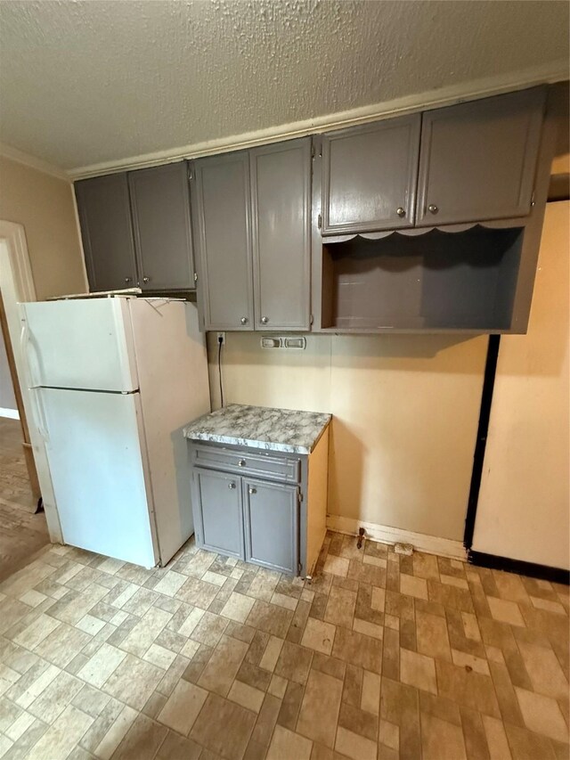 709 Highland Dr, Palestine, TX 75801 - kitchen with freestanding refrigerator, gray cabinets, light countertops, a textured ceiling, and crown molding