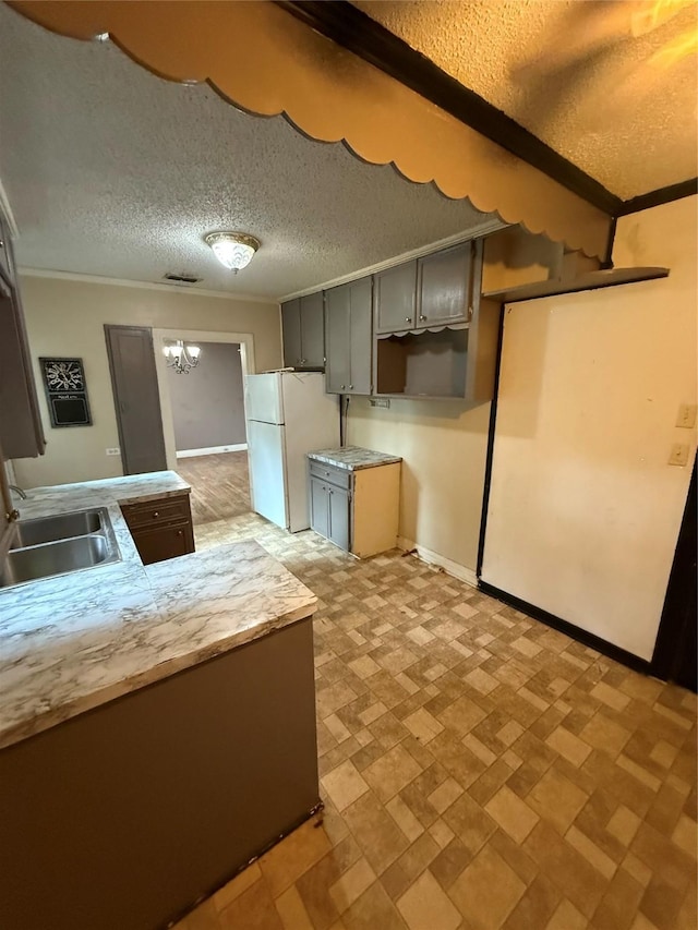 709 Highland Dr, Palestine, TX 75801 - kitchen with freestanding refrigerator, a textured ceiling, a chandelier, ornamental molding, and light countertops