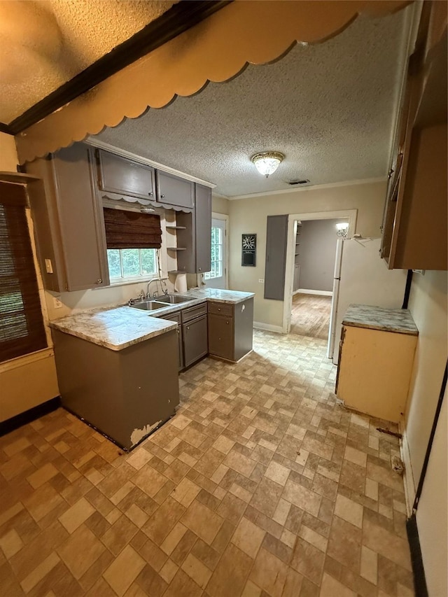 709 Highland Dr, Palestine, TX 75801 - kitchen featuring a peninsula, light countertops, crown molding, gray cabinets, and a textured ceiling