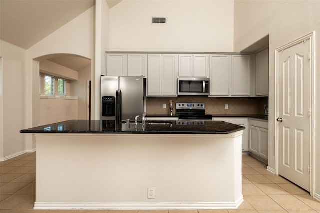 2401 Fawn Meadow Dr, Little Elm, TX 75068 - kitchen with stainless steel appliances, arched walkways, high vaulted ceiling, light tile patterned flooring, and decorative backsplash