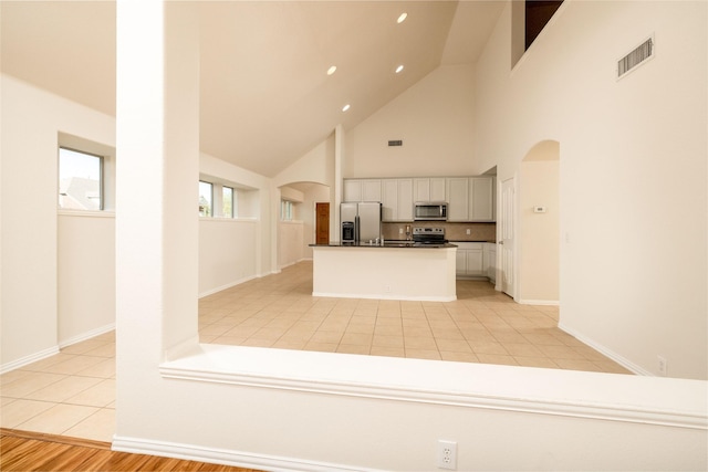 2401 Fawn Meadow Dr, Little Elm, TX 75068 - kitchen with stainless steel appliances, arched walkways, high vaulted ceiling, white cabinetry, and dark countertops