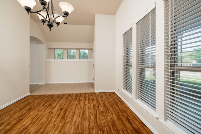 2401 Fawn Meadow Dr, Little Elm, TX 75068 - empty room featuring wood finished floors, a chandelier, plenty of natural light, and arched walkways