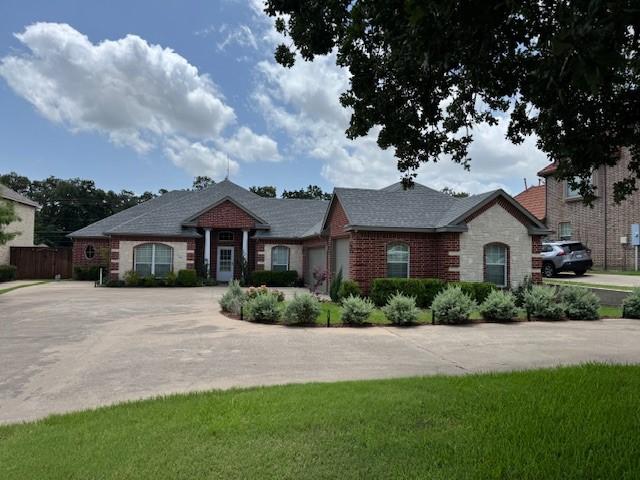 3840 W Pioneer Dr, Irving, TX 75061 - view of front facade featuring driveway, an attached garage, brick siding, and roof with shingles