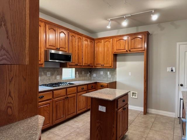 3840 W Pioneer Dr, Irving, TX 75061 - kitchen with stainless steel appliances, brown cabinets, and backsplash