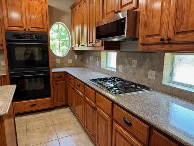 3840 W Pioneer Dr, Irving, TX 75061 - kitchen featuring stainless steel appliances, brown cabinets, backsplash, and light tile patterned floors