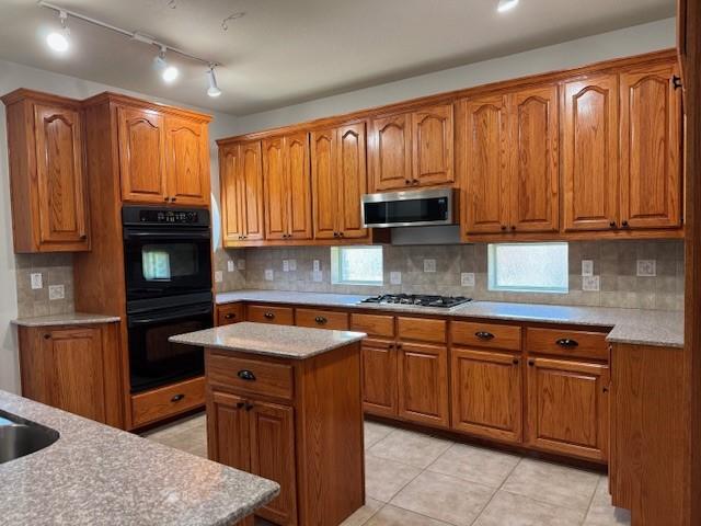 3840 W Pioneer Dr, Irving, TX 75061 - kitchen with stainless steel microwave, brown cabinetry, and gas cooktop