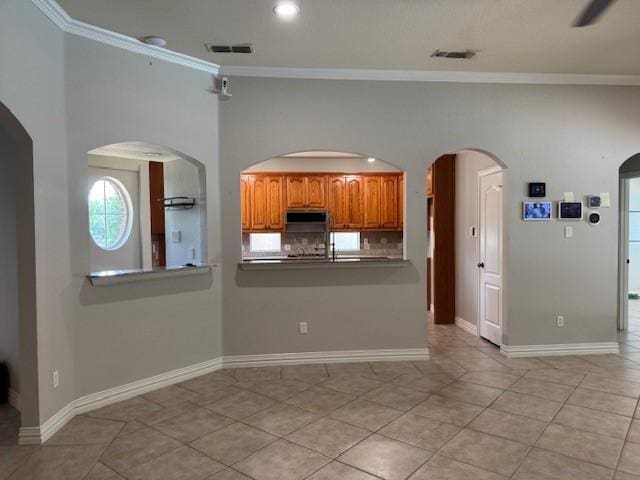 3840 W Pioneer Dr, Irving, TX 75061 - kitchen with crown molding, brown cabinets, light tile patterned flooring, recessed lighting, and decorative backsplash