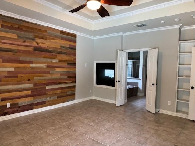 3840 W Pioneer Dr, Irving, TX 75061 - tiled empty room featuring a ceiling fan, crown molding, a tray ceiling, and wood walls