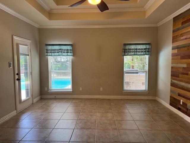 3840 W Pioneer Dr, Irving, TX 75061 - empty room with a tray ceiling, a ceiling fan, crown molding, and tile patterned flooring