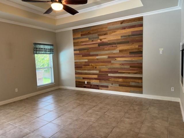 3840 W Pioneer Dr, Irving, TX 75061 - tiled spare room with a tray ceiling, a ceiling fan, ornamental molding, and wooden walls