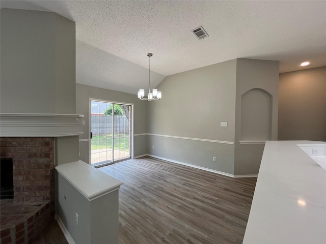 4400 Ripplewood Rd, Frisco, TX 75035 - unfurnished dining area with dark wood-style flooring, a textured ceiling, a chandelier, a fireplace, and vaulted ceiling