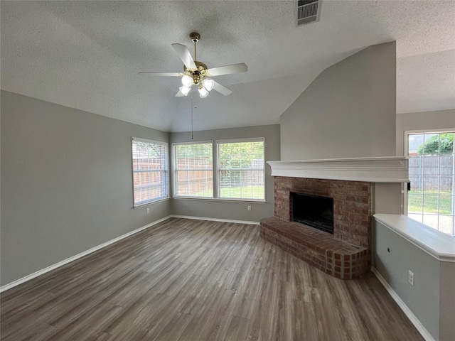 4400 Ripplewood Rd, Frisco, TX 75035 - unfurnished living room featuring a textured ceiling, lofted ceiling, wood finished floors, ceiling fan, and a fireplace