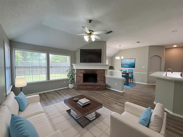 4400 Ripplewood Rd, Frisco, TX 75035 - living area featuring vaulted ceiling, wood finished floors, ceiling fan, a fireplace, and a chandelier