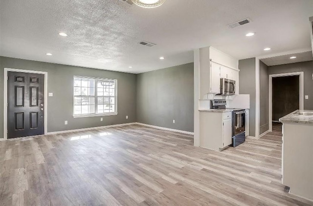 3501 NE 10th St, Mineral Wells, TX 76067 - kitchen featuring electric range oven, stainless steel microwave, white cabinetry, light wood-style flooring, and light countertops