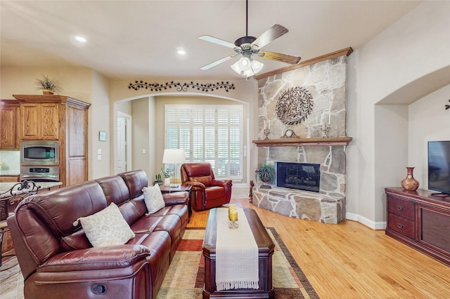 5768 Gallant Run, Frisco, TX 75033 - living room featuring arched walkways, wood finished floors, ceiling fan, a stone fireplace, and recessed lighting