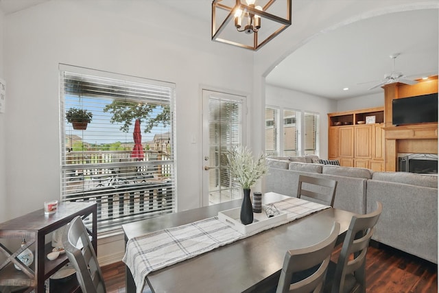 1128 Bent Oaks Dr, Denton, TX 76210 - dining space with arched walkways, dark wood-style flooring, a ceiling fan, a tiled fireplace, and a chandelier