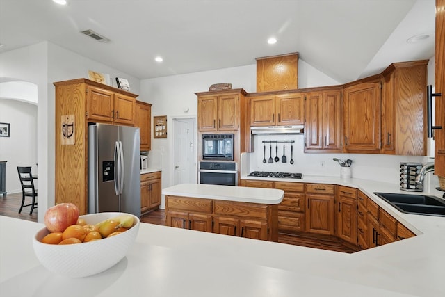 1128 Bent Oaks Dr, Denton, TX 76210 - kitchen featuring appliances with stainless steel finishes, under cabinet range hood, light countertops, arched walkways, and brown cabinetry
