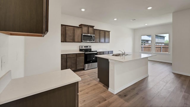 414 Drake Dr, Ferris, TX 75125 - kitchen with stainless steel appliances, light wood-type flooring, dark brown cabinetry, recessed lighting, and light countertops