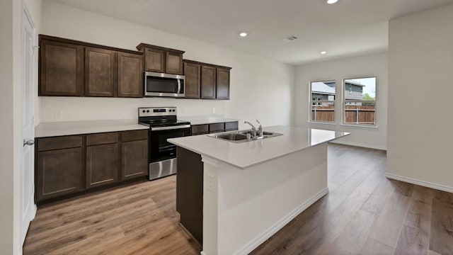 414 Drake Dr, Ferris, TX 75125 - kitchen with stainless steel appliances, light wood-style flooring, recessed lighting, light countertops, and a center island with sink