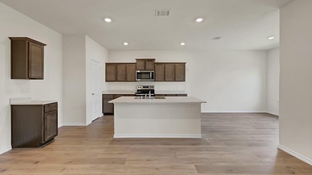 414 Drake Dr, Ferris, TX 75125 - kitchen featuring appliances with stainless steel finishes, a kitchen island with sink, light wood-type flooring, light countertops, and recessed lighting