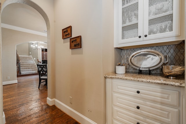 126 Yorkshire Dr, Heath, TX 75032 - bar area with arched walkways, dark wood-style flooring, stairway, decorative backsplash, and a chandelier