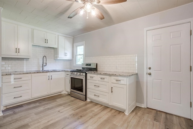 4944 Royal Dr, Fort Worth, TX 76116 - kitchen featuring stainless steel range with gas stovetop, ceiling fan, white cabinets, light wood-style flooring, and ornamental molding