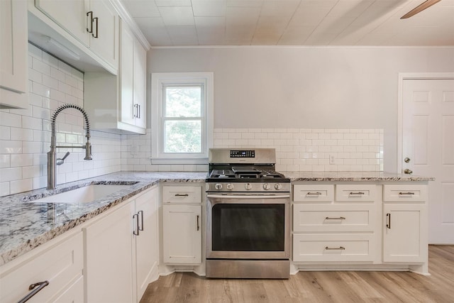 4944 Royal Dr, Fort Worth, TX 76116 - kitchen with stainless steel range with gas stovetop, ornamental molding, light wood finished floors, tasteful backsplash, and white cabinetry