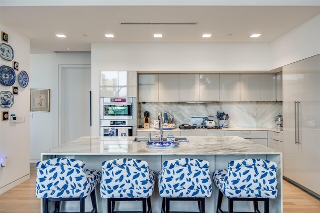 1918 Olive St Unit 502, Dallas, TX 75201 - kitchen featuring modern cabinets, gray cabinets, a kitchen breakfast bar, light wood-style floors, and recessed lighting